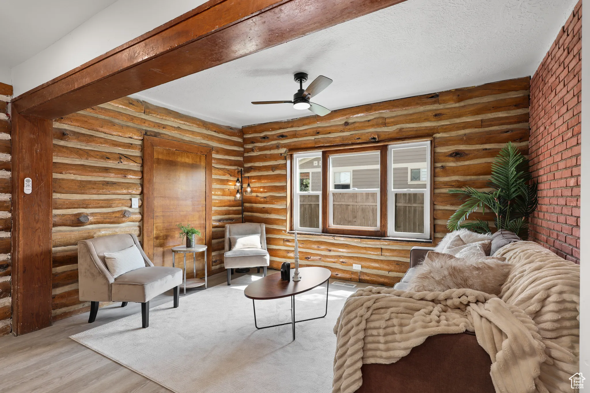 Sitting room featuring a ceiling fan, wood finished floors, rustic walls, and a textured ceiling