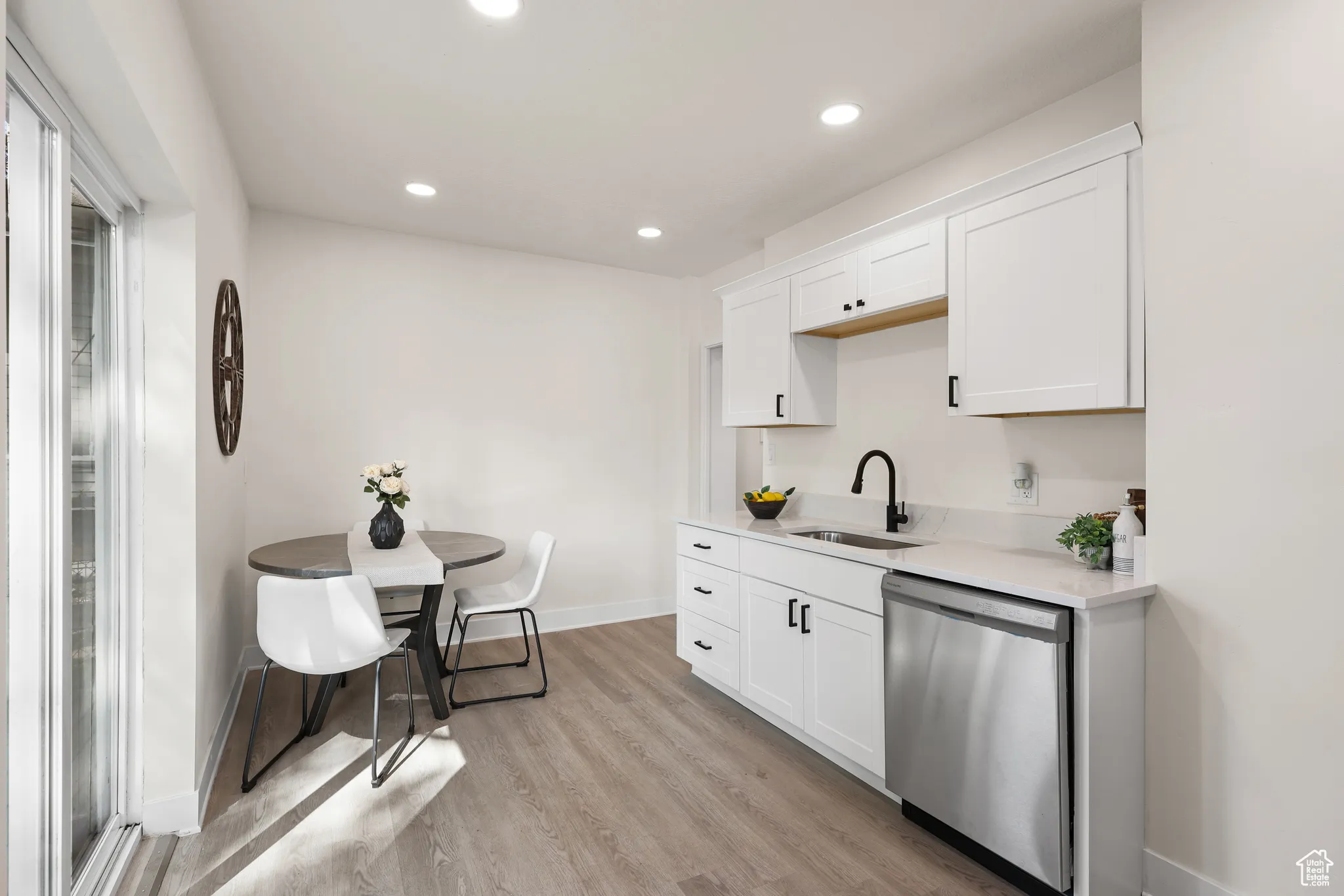 Kitchen with dishwasher, white cabinets, recessed lighting, light wood-style floors, and light stone counters