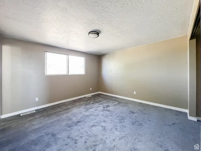 Spare room with dark colored carpet and a textured ceiling