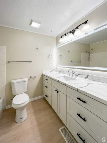 Bathroom with vanity, wood finished floors, a textured ceiling, and shower / washtub combination
