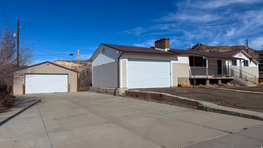 View of front of property with a chimney, covered porch, and a garage