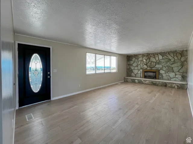 Foyer entrance with a textured ceiling, wood finished floors, and a fireplace