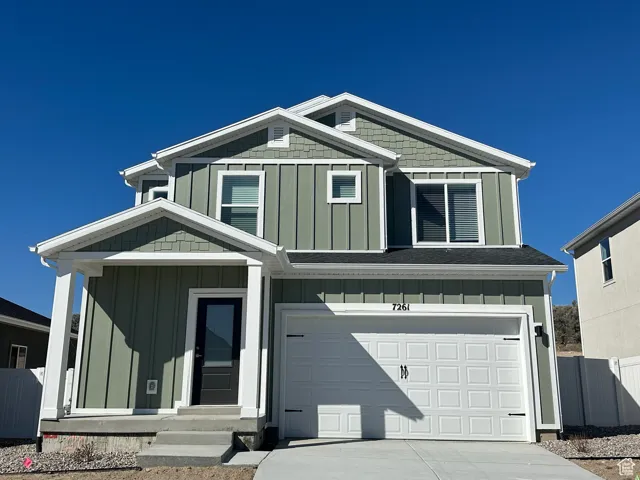 View of front of property featuring board and batten siding, driveway, an attached garage, and entry steps