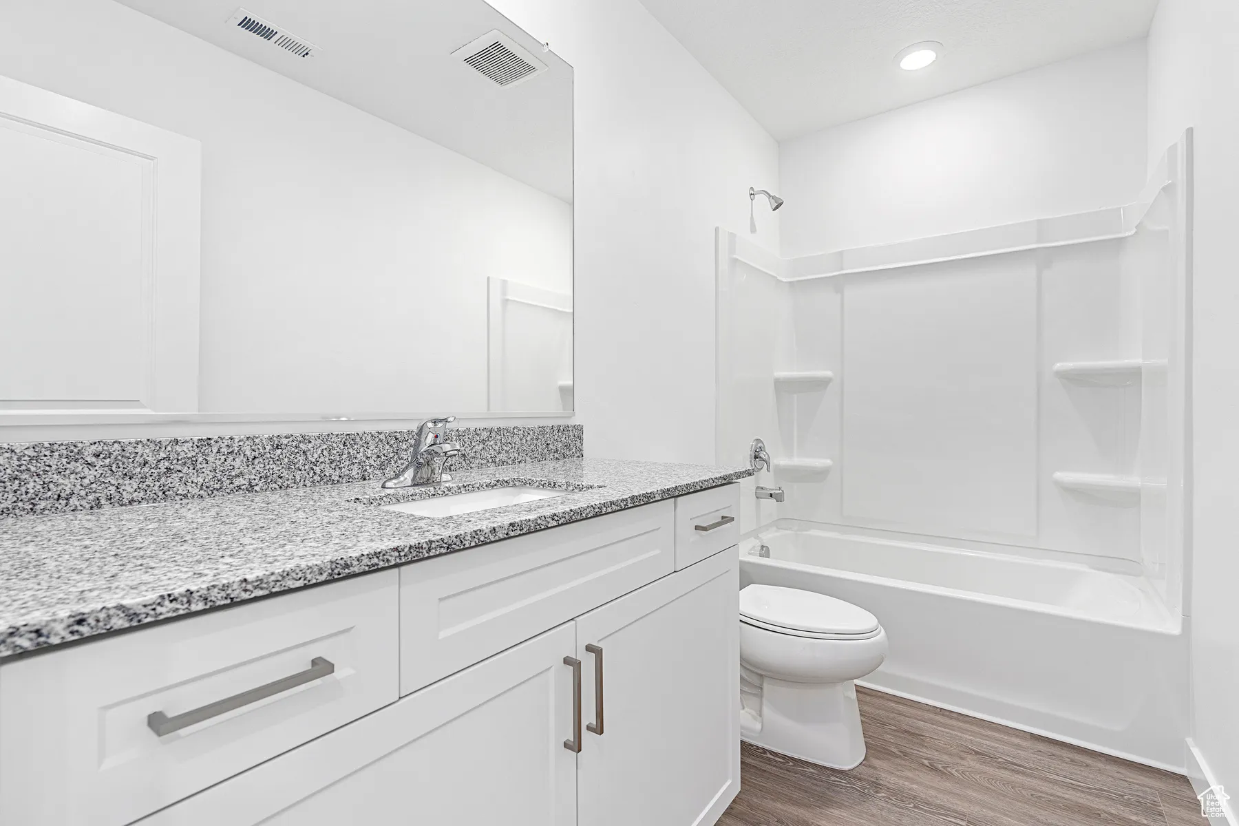 Bathroom featuring vanity, wood finished floors, and shower / washtub combination