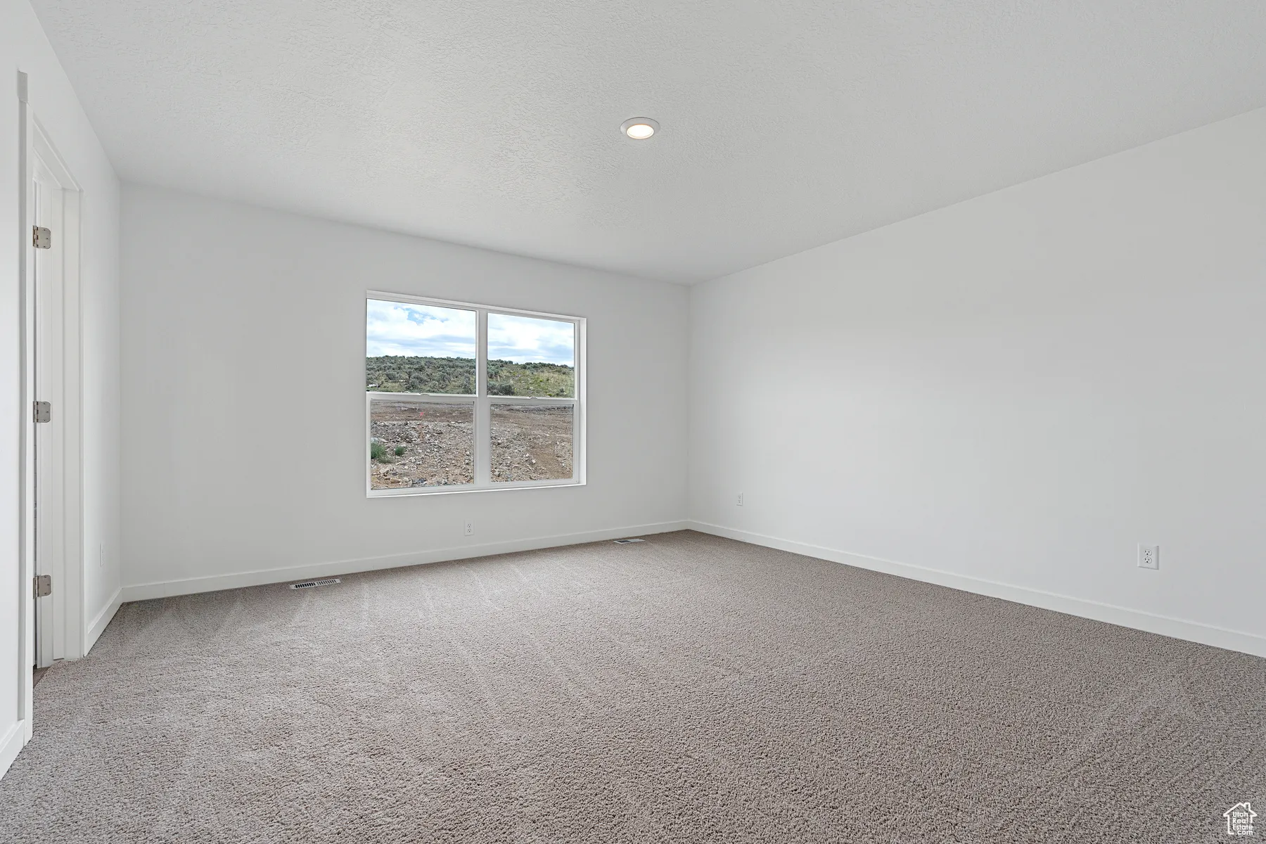 Carpeted spare room with a textured ceiling and recessed lighting