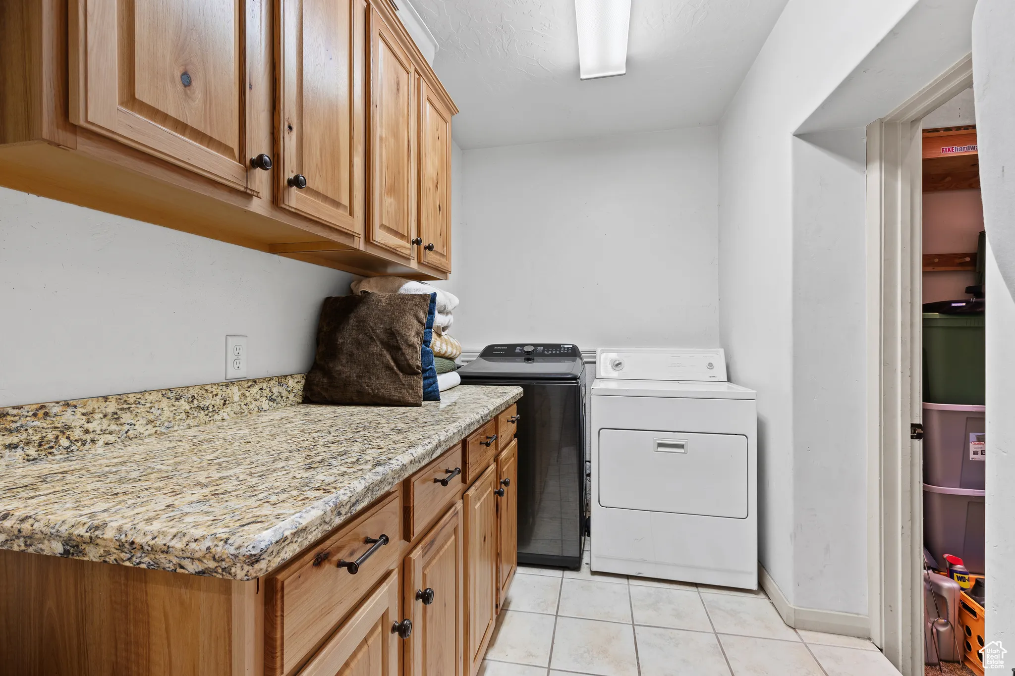 Laundry area with separate washer and dryer, light tile patterned flooring, and cabinet space