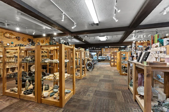 Misc room featuring beamed ceiling, rail lighting, carpet, and a textured ceiling