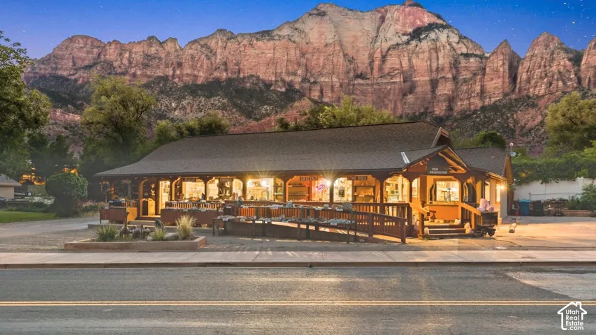 Single-story structure featuring a covered wrap-around porch, wood-shingle roofing, an integrated accessibility ramp, and prominent mountain backdrop