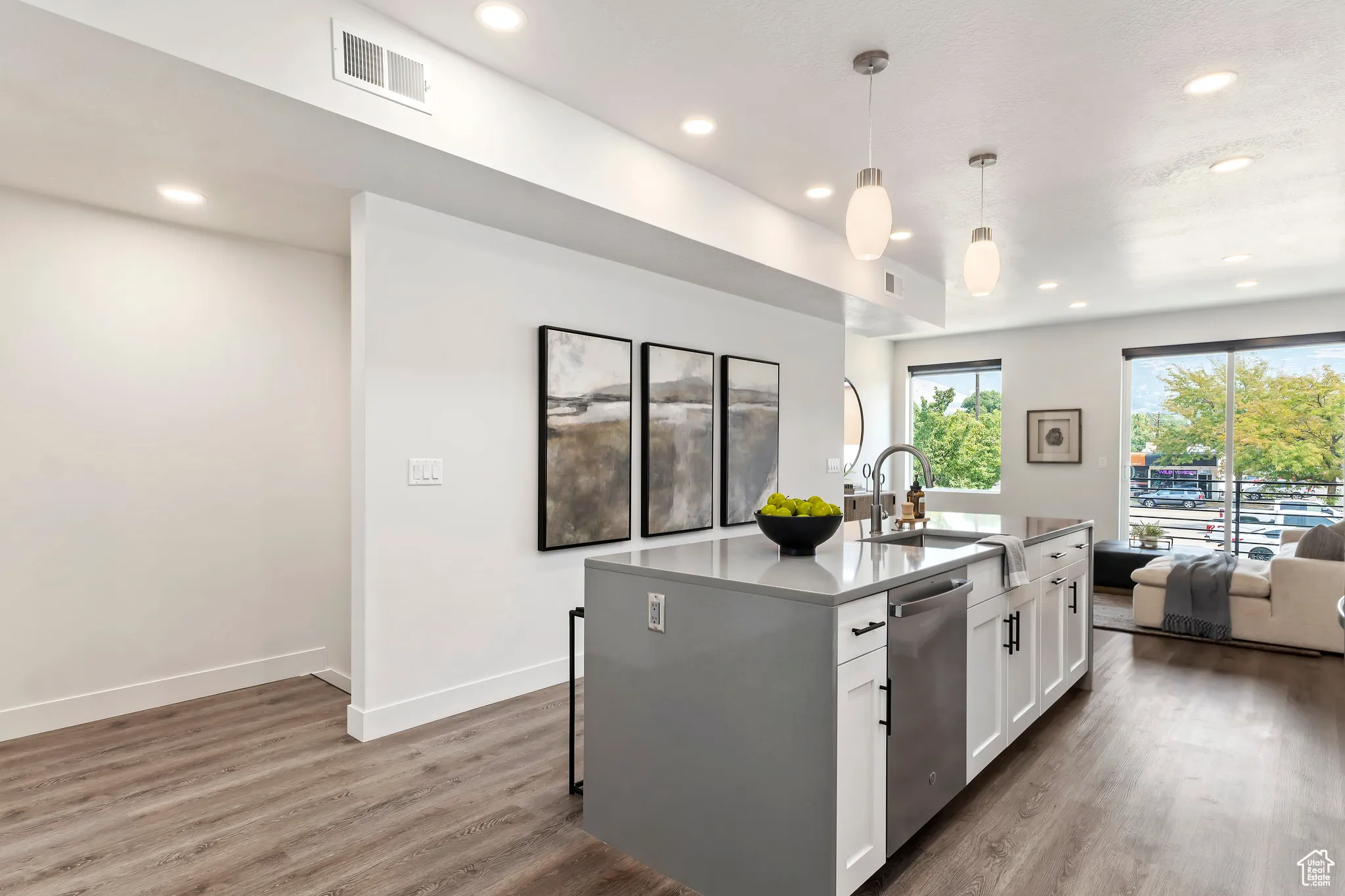 Kitchen featuring open floor plan, wood finished floors, white cabinetry, recessed lighting, and stainless steel dishwasher