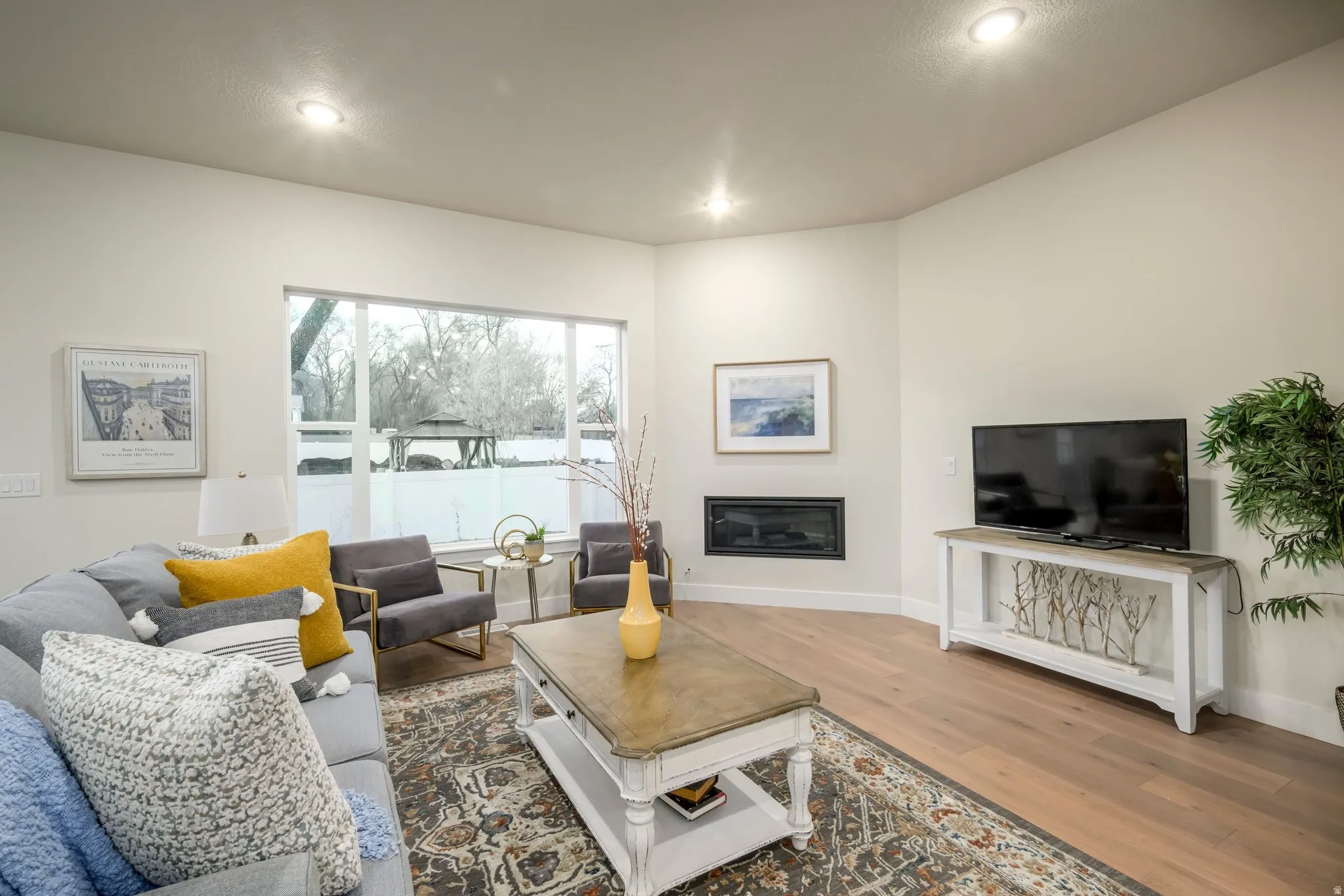 Living area featuring a glass covered fireplace, wood finished floors, and recessed lighting