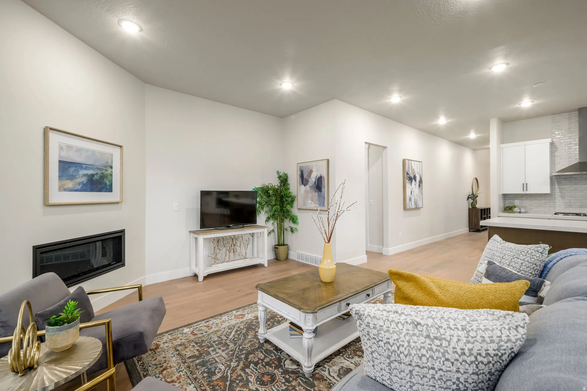 Living area featuring light wood finished floors, a glass covered fireplace, and recessed lighting