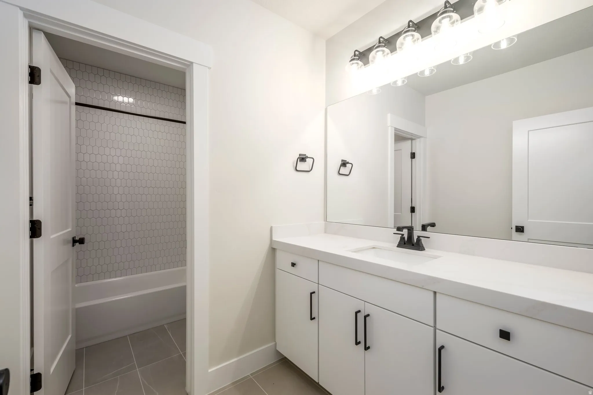 Bathroom with vanity, shower / bathtub combination, and light tile patterned floors