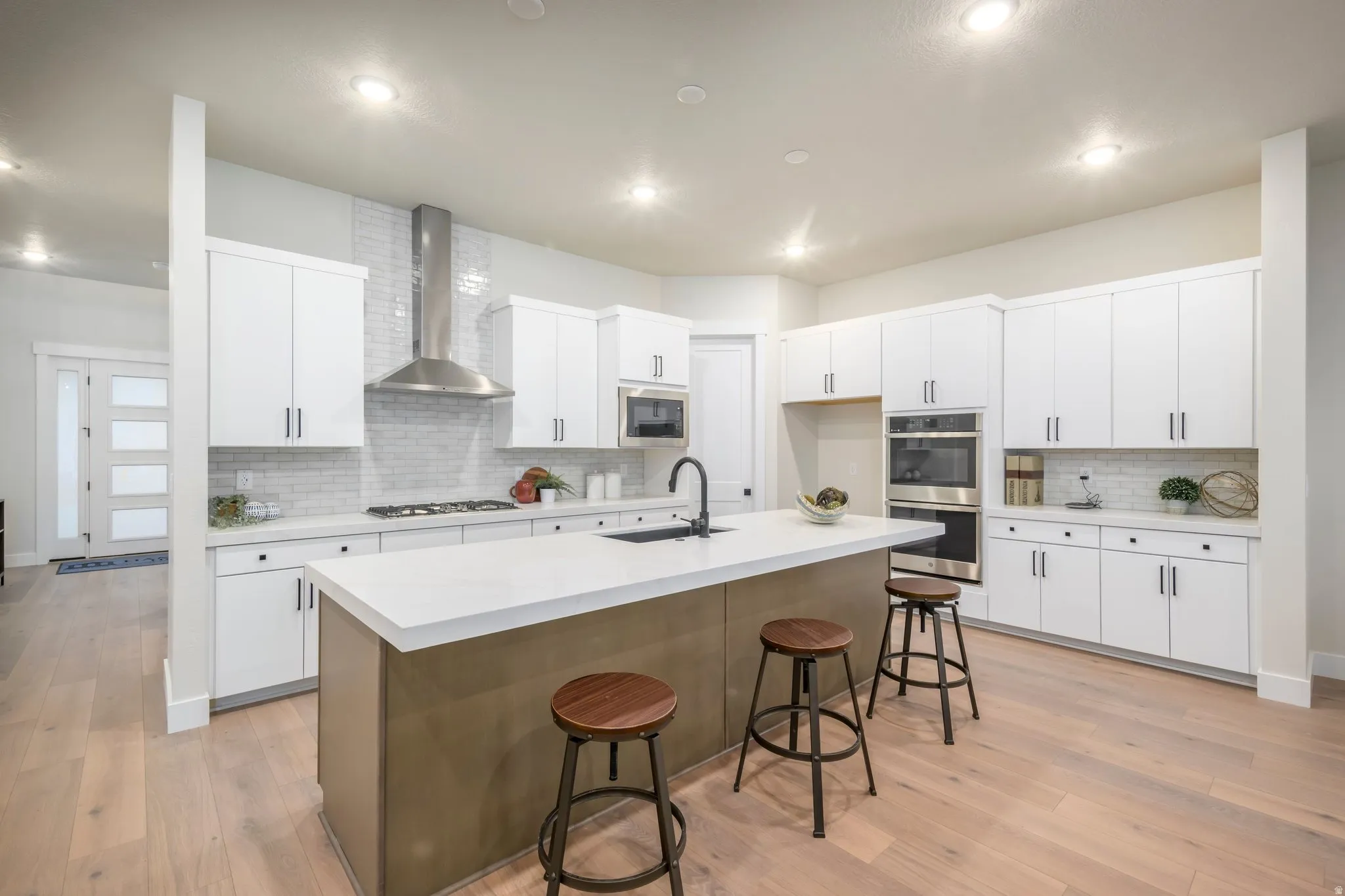 Kitchen featuring a kitchen breakfast bar, light wood finished floors, a kitchen island with sink, stainless steel appliances, and recessed lighting