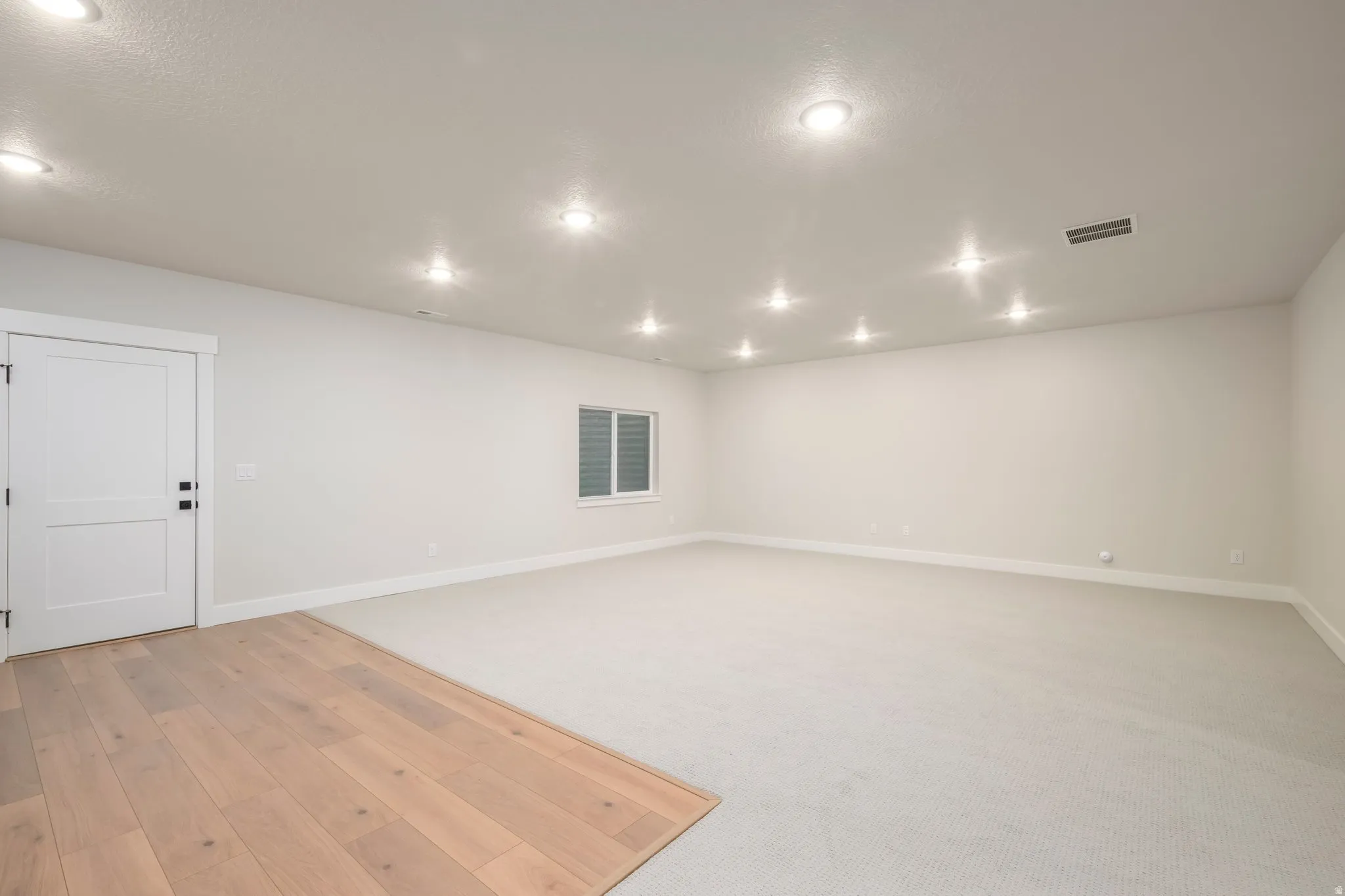 Spare room featuring recessed lighting, light colored carpet, and light wood finished floors