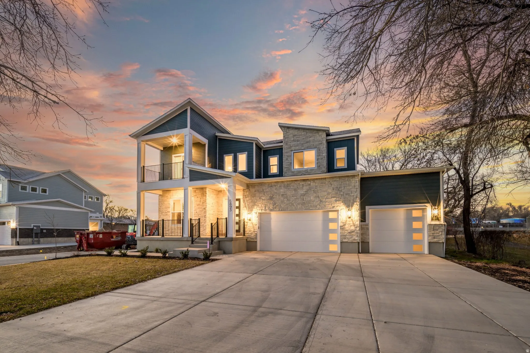 Contemporary home with stone siding, concrete driveway, a front yard, a porch, and an attached garage