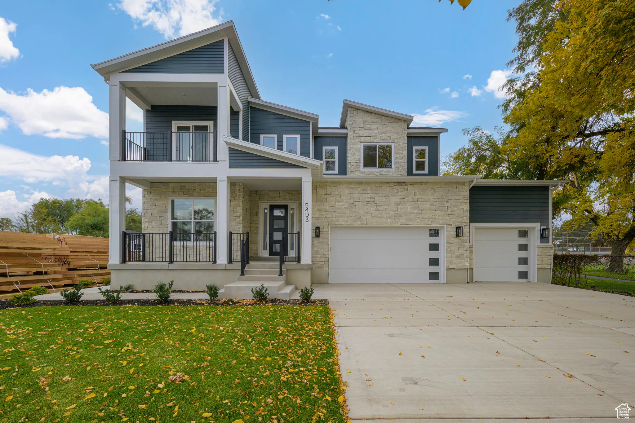 Modern home with stone siding, a porch, driveway, and an attached garage