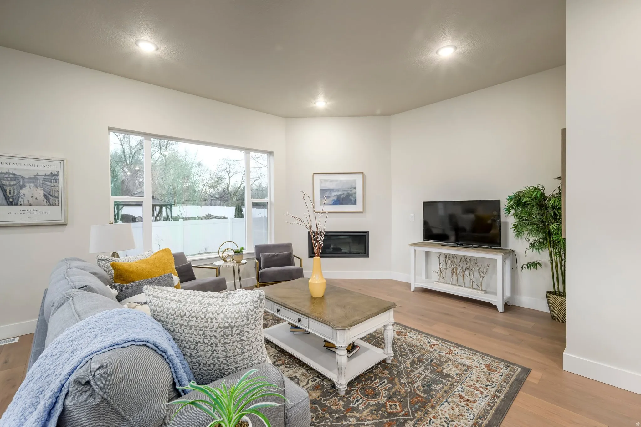 Living area featuring light wood-style floors, a glass covered fireplace, and recessed lighting