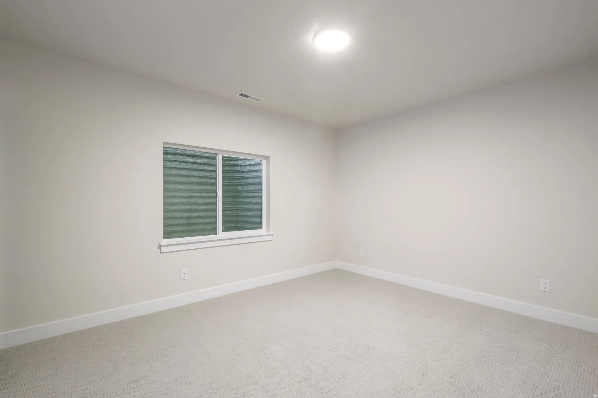 Carpeted spare room featuring baseboards