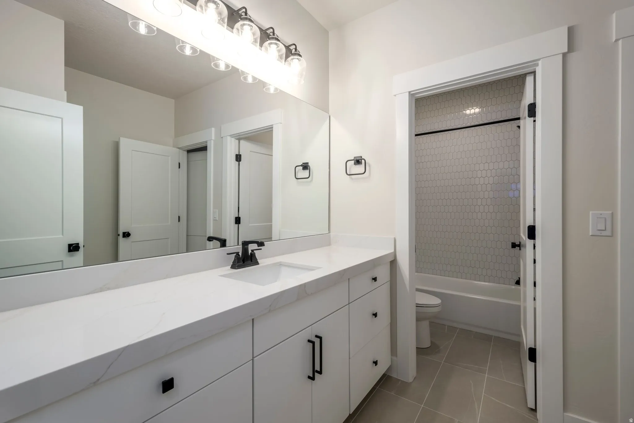 Full bath featuring vanity, shower / bathtub combination with curtain, and light tile patterned flooring