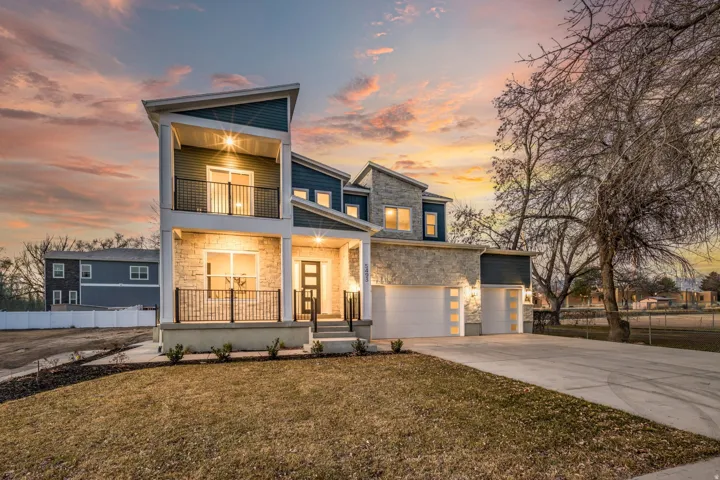 Contemporary house featuring stone siding, a porch, driveway, a garage, and a balcony