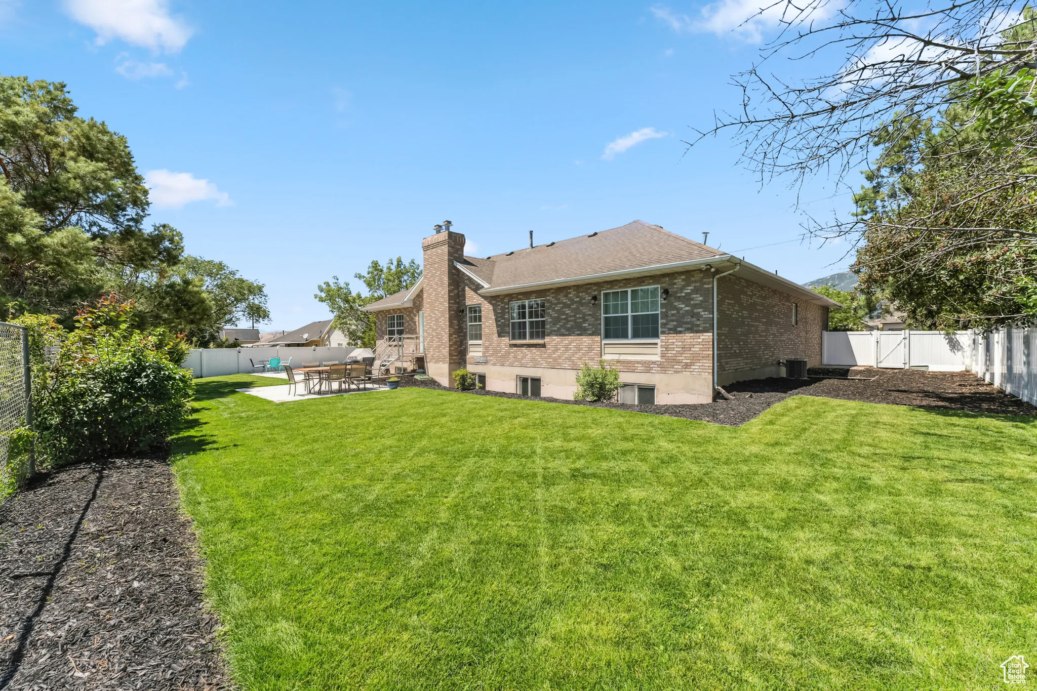 Rear view of house featuring brick siding, a fenced backyard, a patio, and a chimney