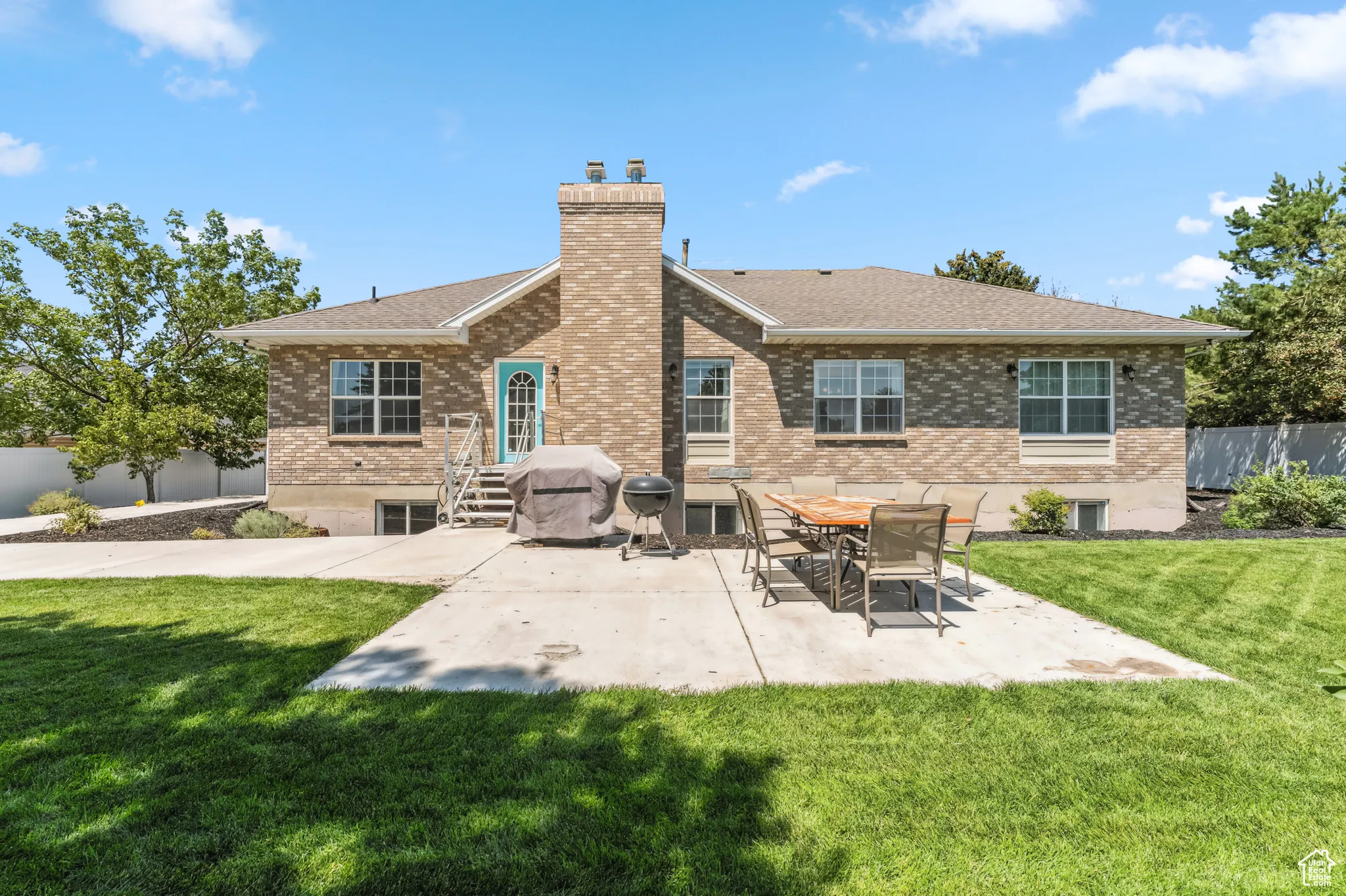Back of property featuring brick siding, a chimney, a patio area, and a shingled roof