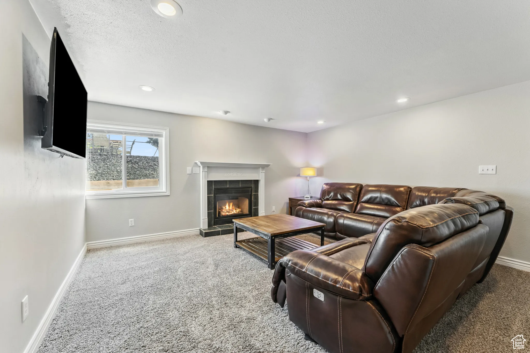 Living room with a fireplace, carpet, recessed lighting, and a textured ceiling