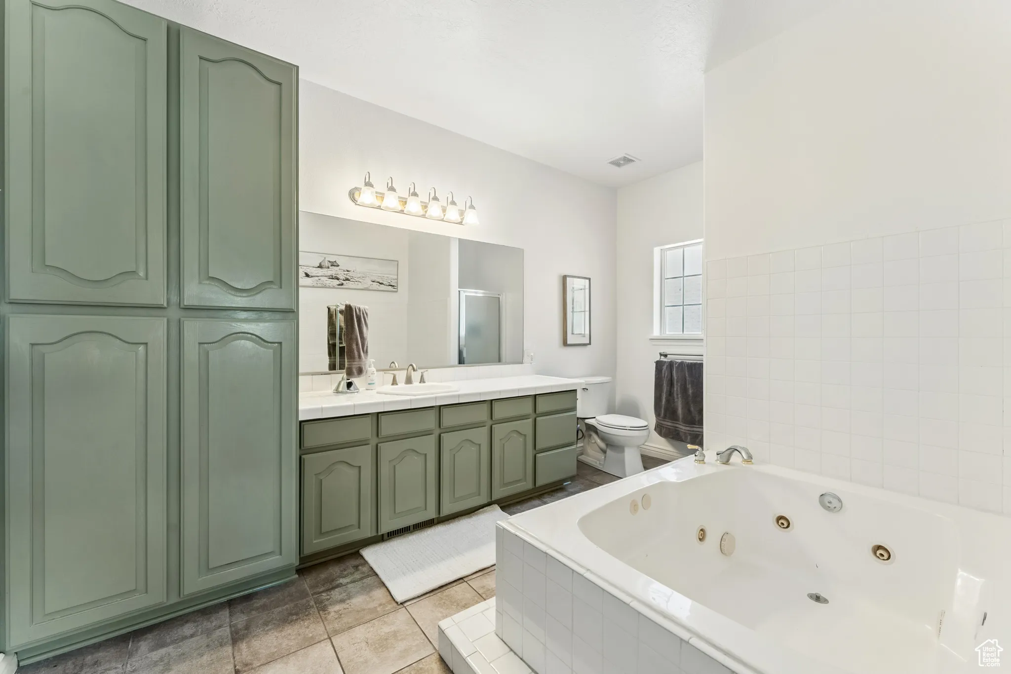 Full bathroom featuring a jetted tub, vanity, tile patterned flooring, and a shower