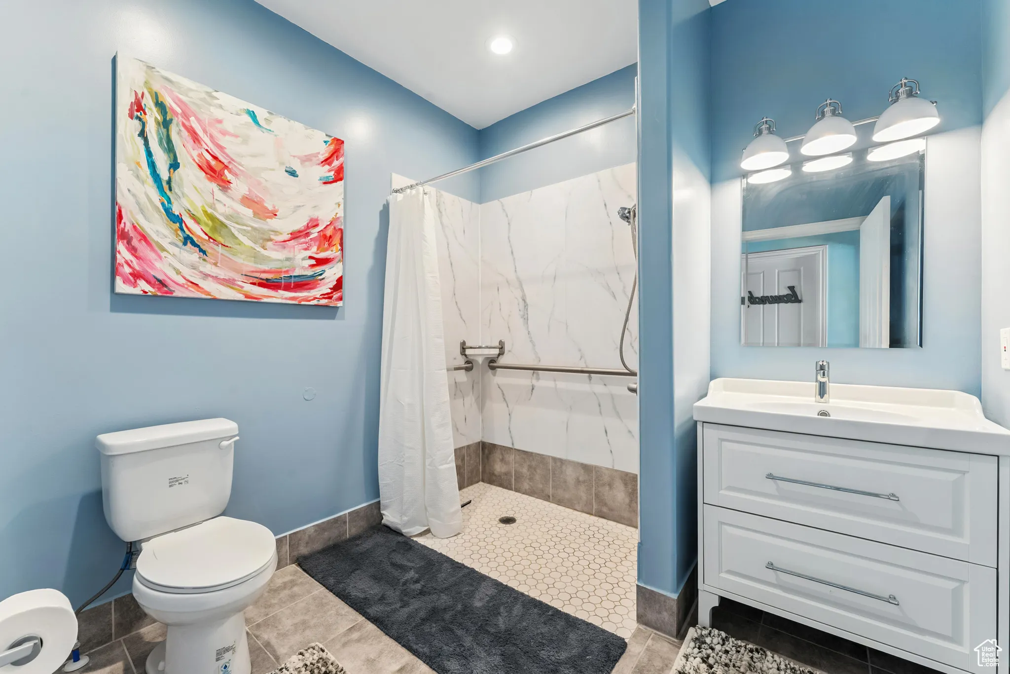 Bathroom featuring a marble finish shower, vanity, and tile patterned floors