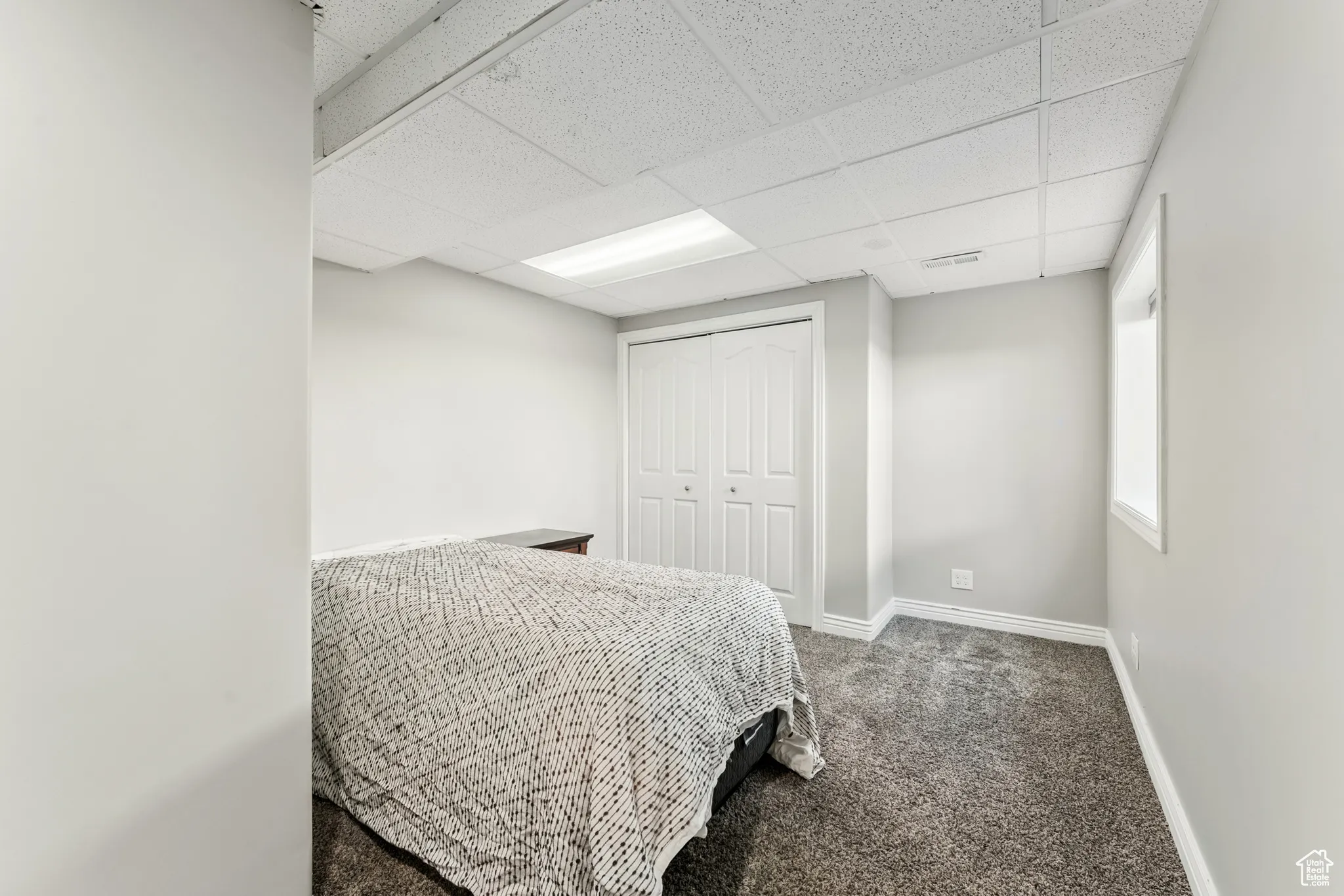Carpeted bedroom featuring a paneled ceiling and a closet