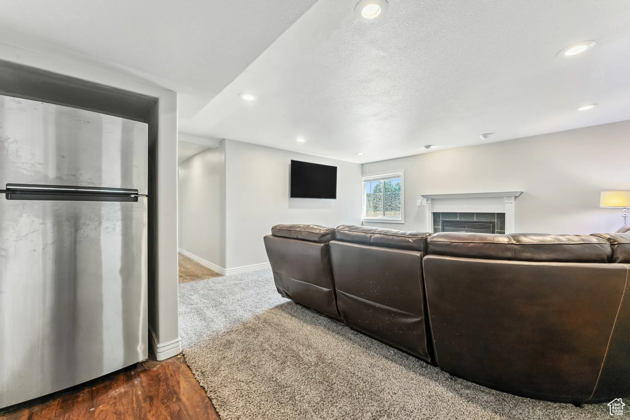 Carpeted living area featuring wood finished floors, a tile fireplace, a textured ceiling, and recessed lighting