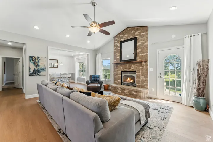 Living area featuring a ceiling fan, light wood-style floors, a brick fireplace, recessed lighting, and high vaulted ceiling