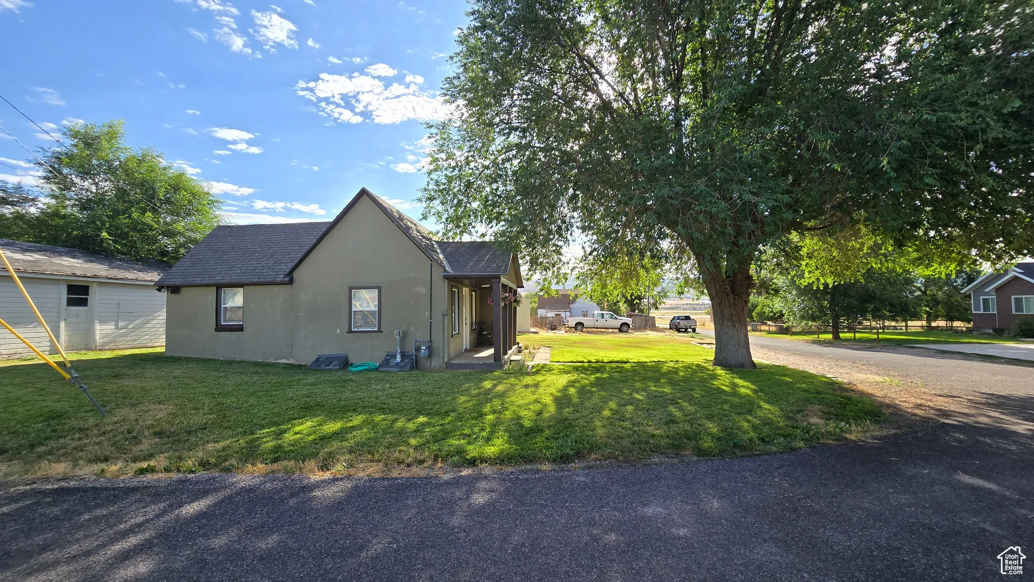 View of property exterior with stucco siding, a lawn, and roof with shingles