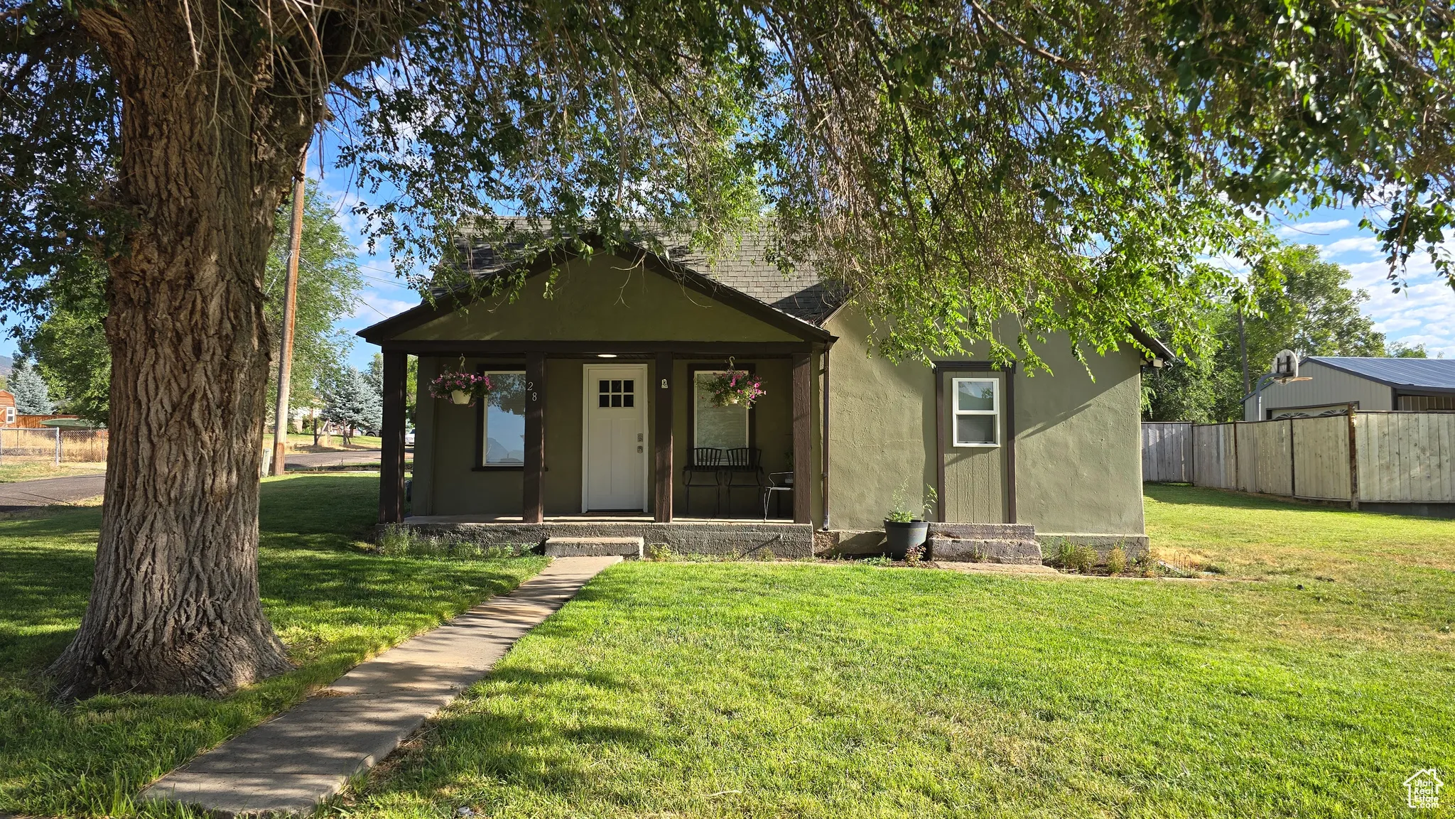 View of front of home featuring covered porch, a shingled roof, and stucco siding