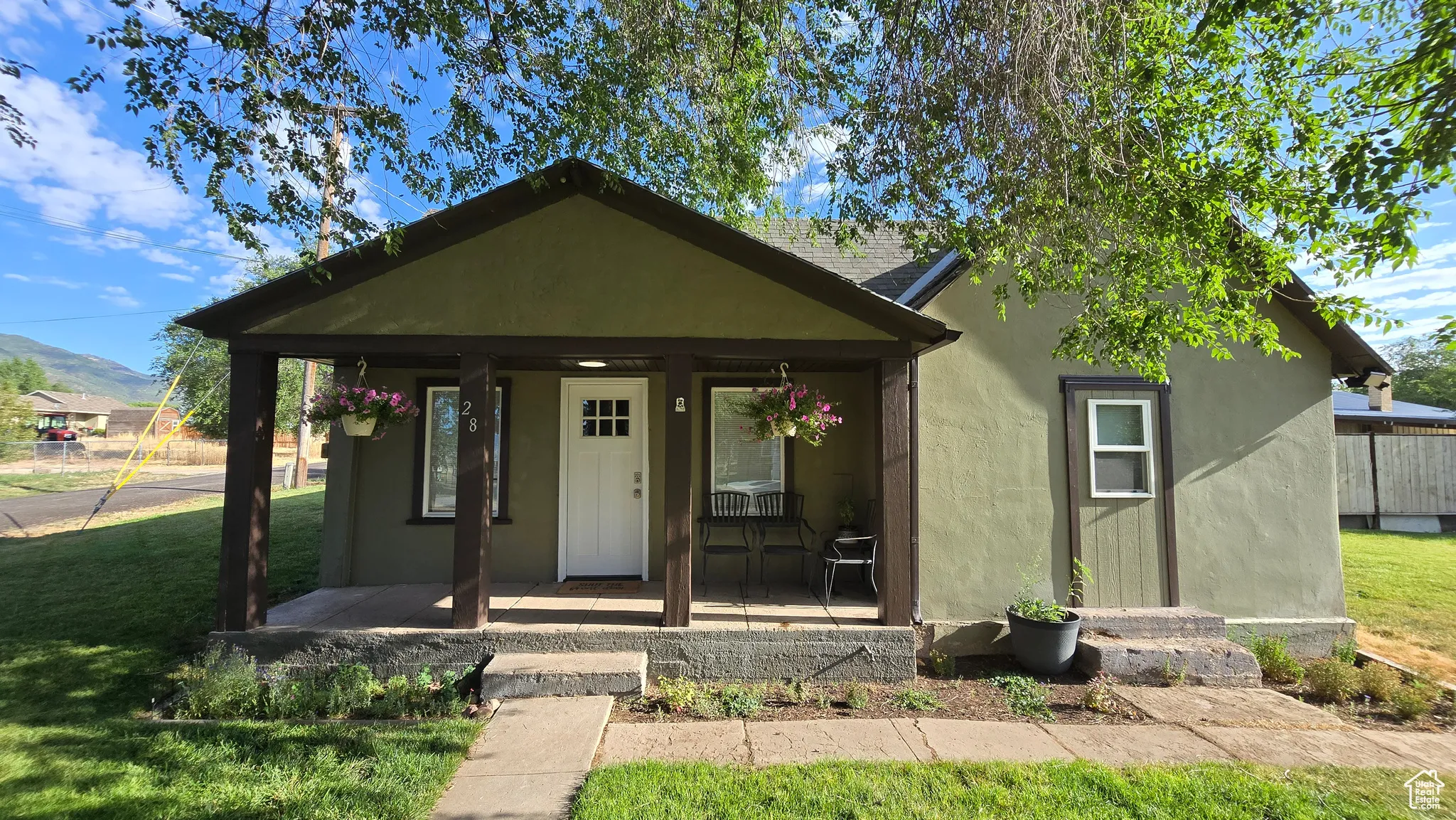 Bungalow with covered porch, a front lawn, and stucco siding