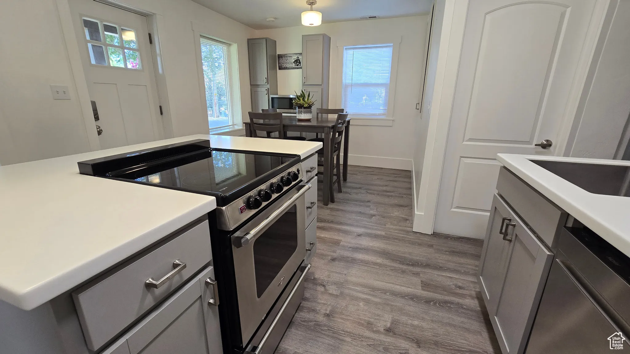 Kitchen featuring electric range, gray cabinets, dark wood-type flooring, light countertops, and pendant lighting