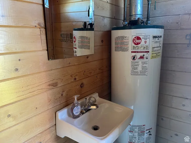 Bathroom featuring gas water heater, wooden walls, and water heater