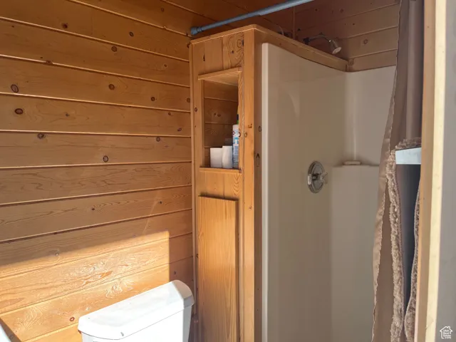 Bathroom featuring wooden walls and curtained shower