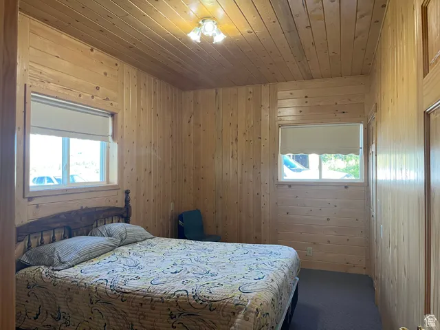 Carpeted bedroom with wood ceiling and wooden walls