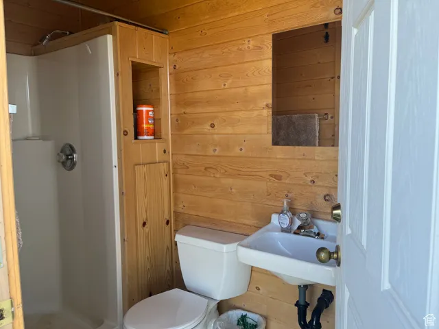 Full bathroom featuring wooden walls and a shower stall