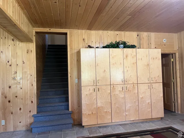 Stairs with wood ceiling, wood walls, and tile patterned flooring