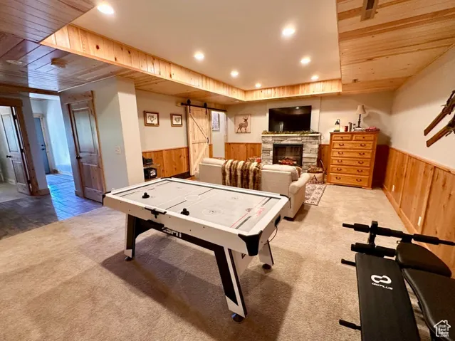 Rec room featuring a wainscoted wall, wooden walls, recessed lighting, carpet flooring, and a barn door