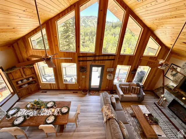 Living room with a ceiling fan, wood ceiling, high vaulted ceiling, wood walls, and wood finished floors