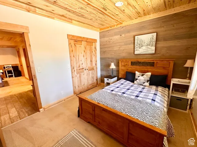 Bedroom with wood ceiling, wooden walls, carpet, and a closet