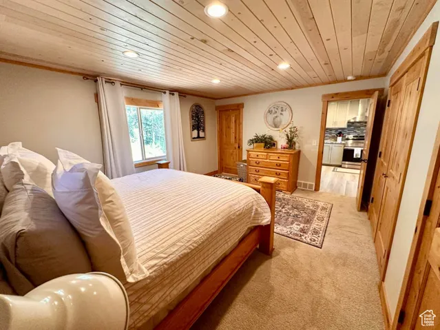 Bedroom with wood ceiling, recessed lighting, and light colored carpet