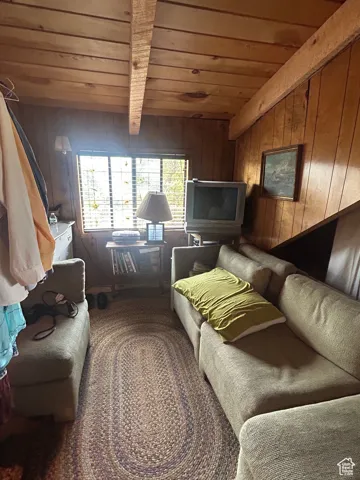 Living room with a wooden ceiling with exposed beams and wooden walls