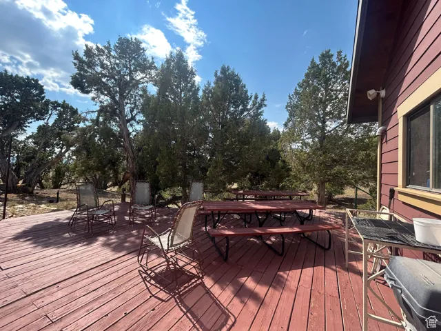 Wooden terrace featuring outdoor dining space and view of scattered trees