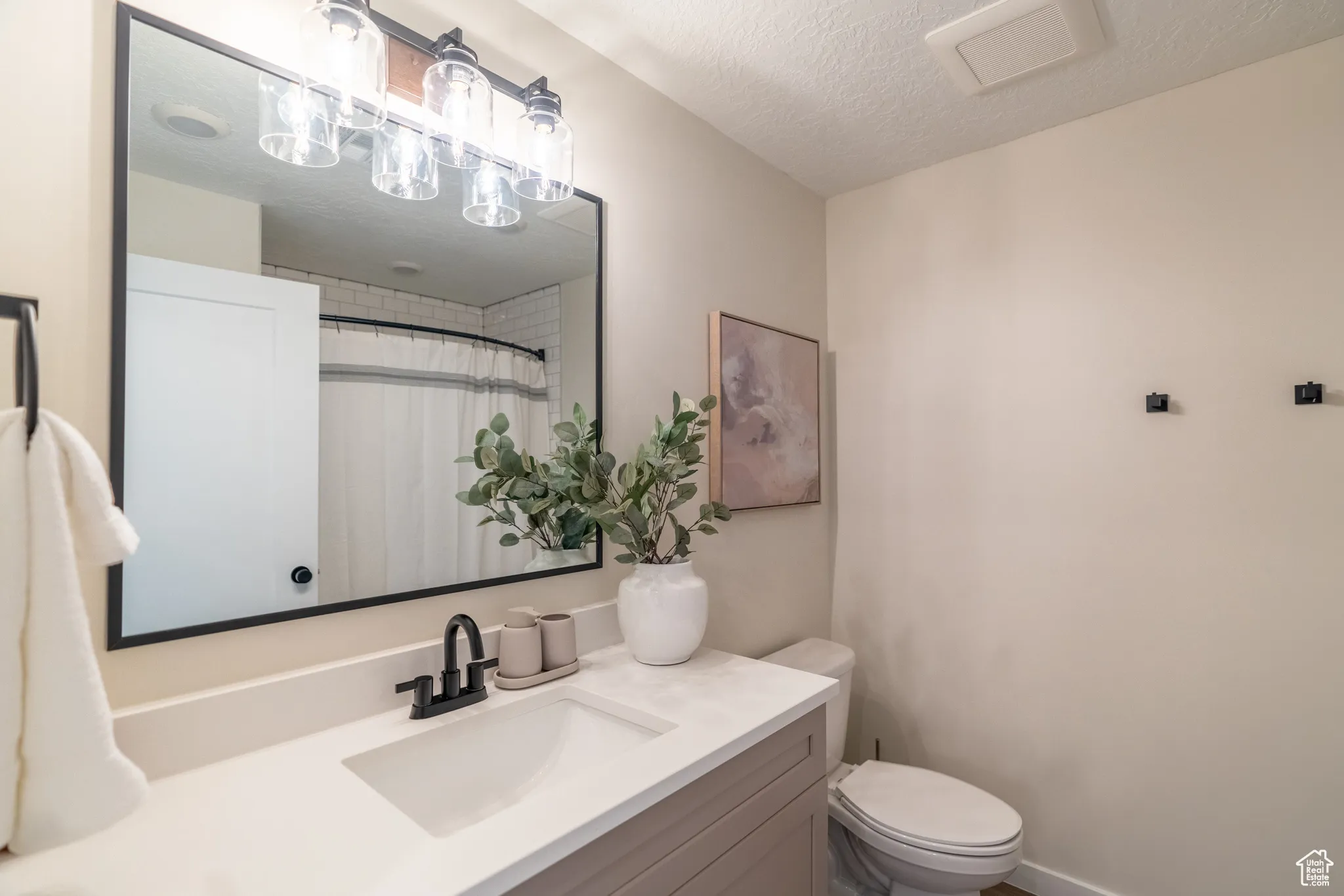 Bathroom featuring a textured ceiling, vanity, and curtained shower
