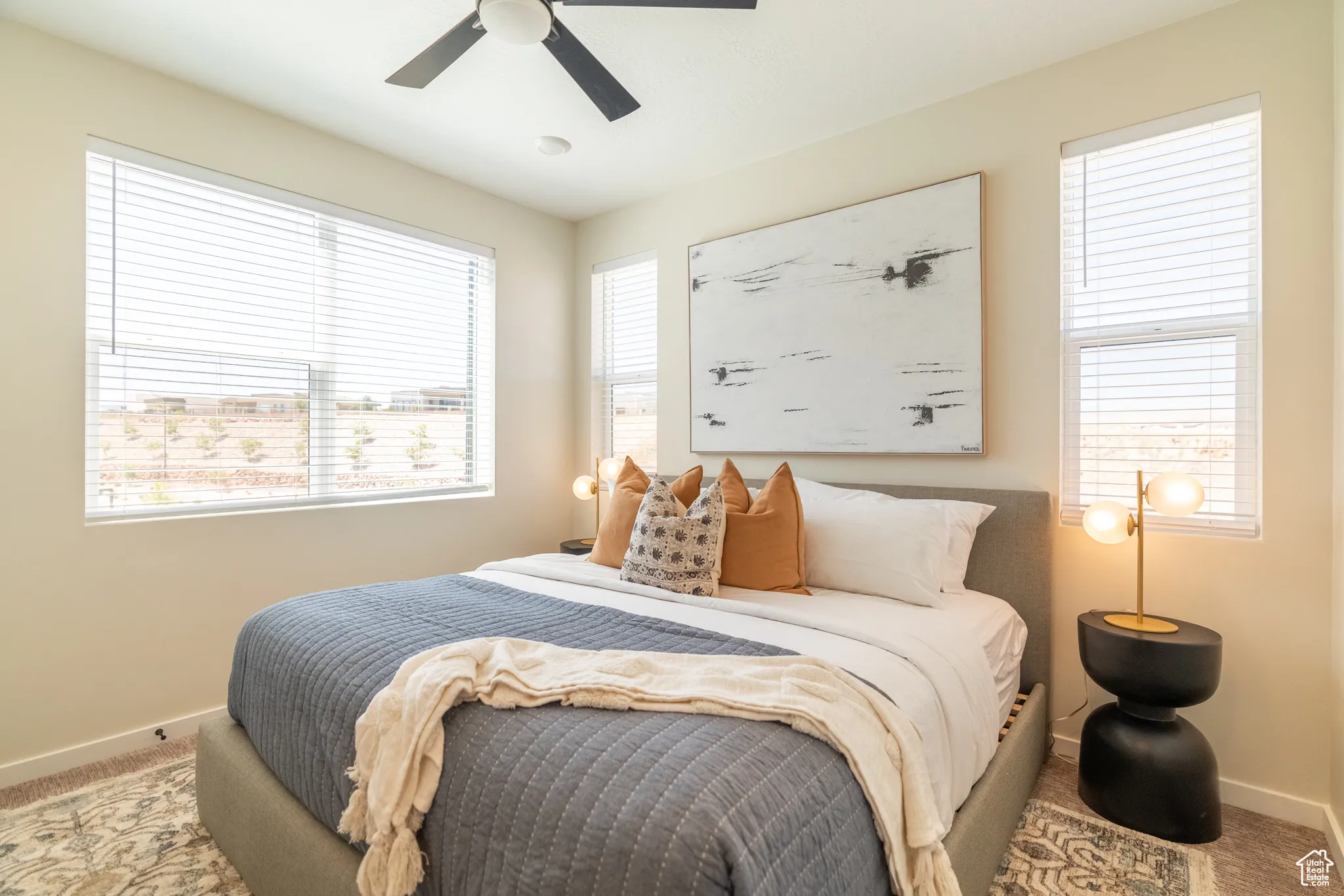 Carpeted bedroom featuring multiple windows and ceiling fan
