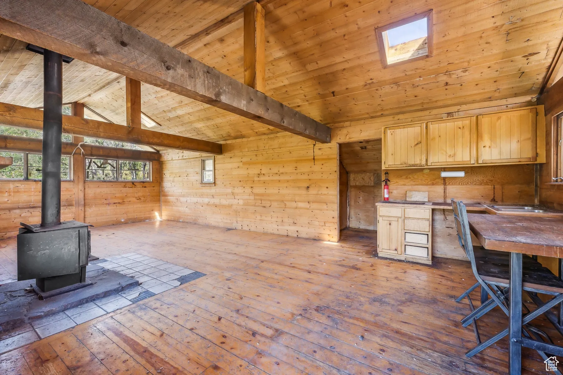 Unfurnished office featuring hardwood / wood-style flooring, a wood stove, wood ceiling, and wooden walls